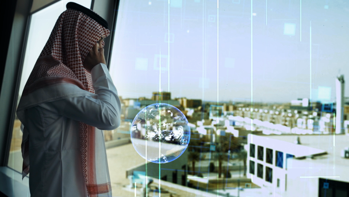 A Saudi Gulf businessman looking out of the window of his office, talking on his mobile phone, and using the other hand to move around, using hologram technology