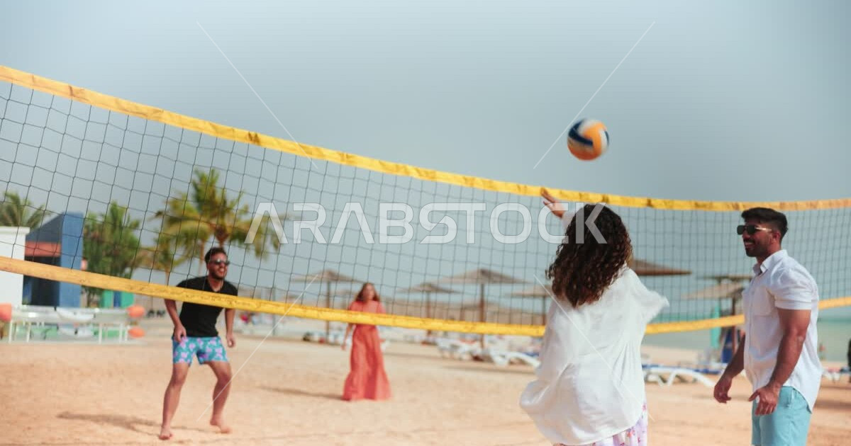 A group of Saudi Arabian Gulf friends playing beach volleyball on the