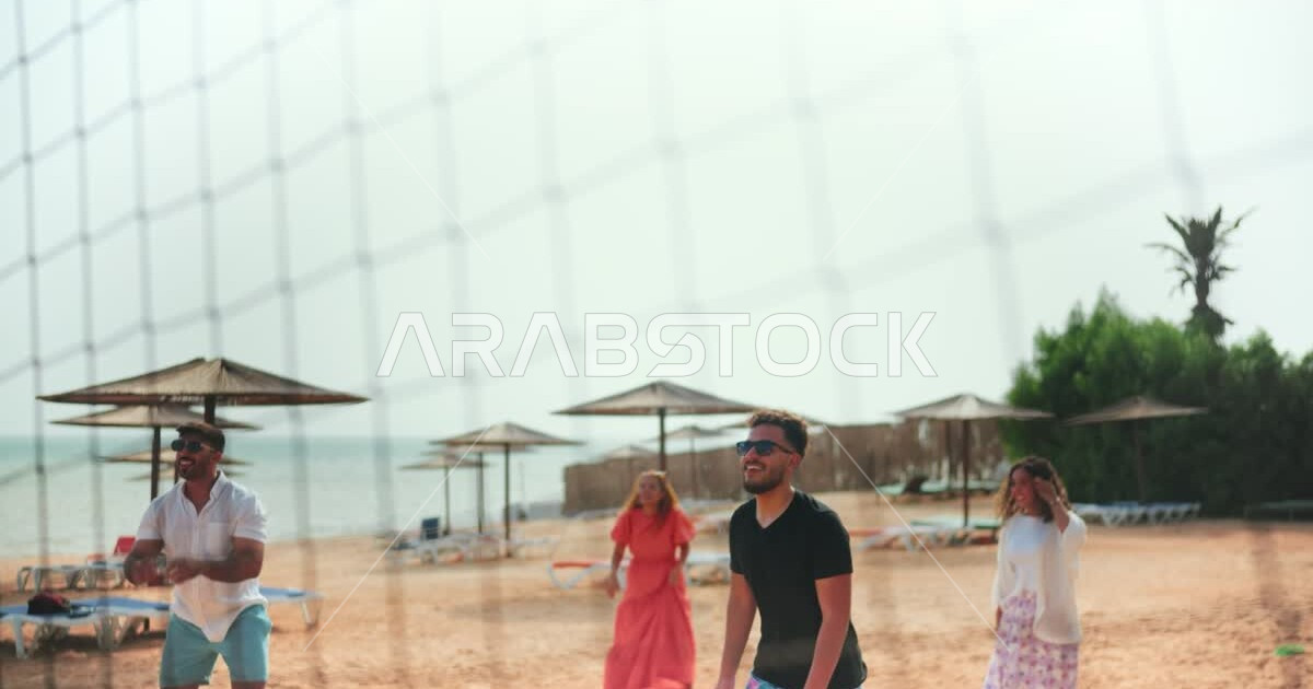 A group of Saudi Arabian Gulf friends playing beach volleyball on the