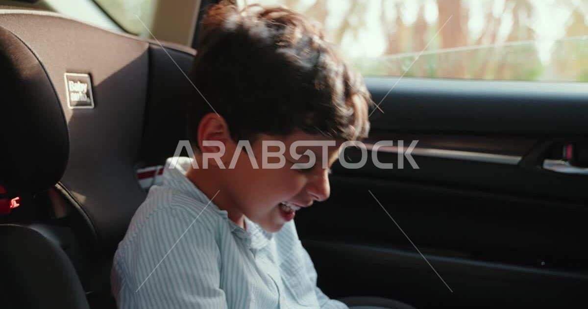 Closeup of a Saudi Arabian Gulf child riding in the back seat of a car