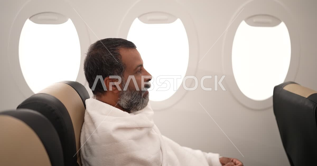 A Saudi Arabian Gulf man from inside the plane, wearing the Ihram dress ...