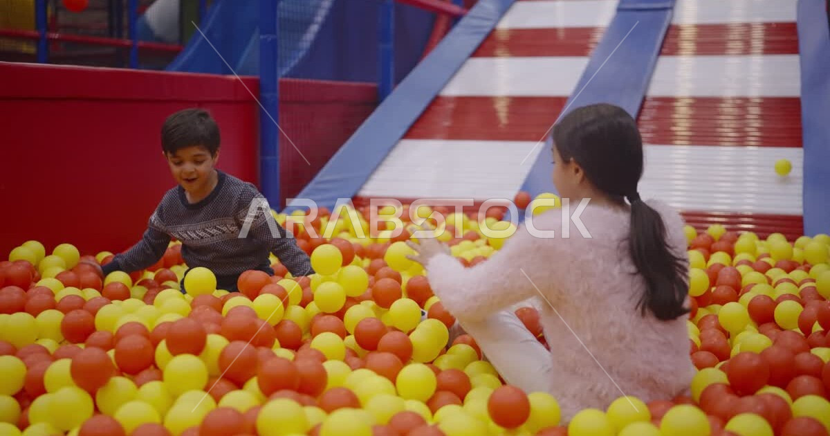 Two Saudi Arabian Gulf children enjoying playing on a skating game ...
